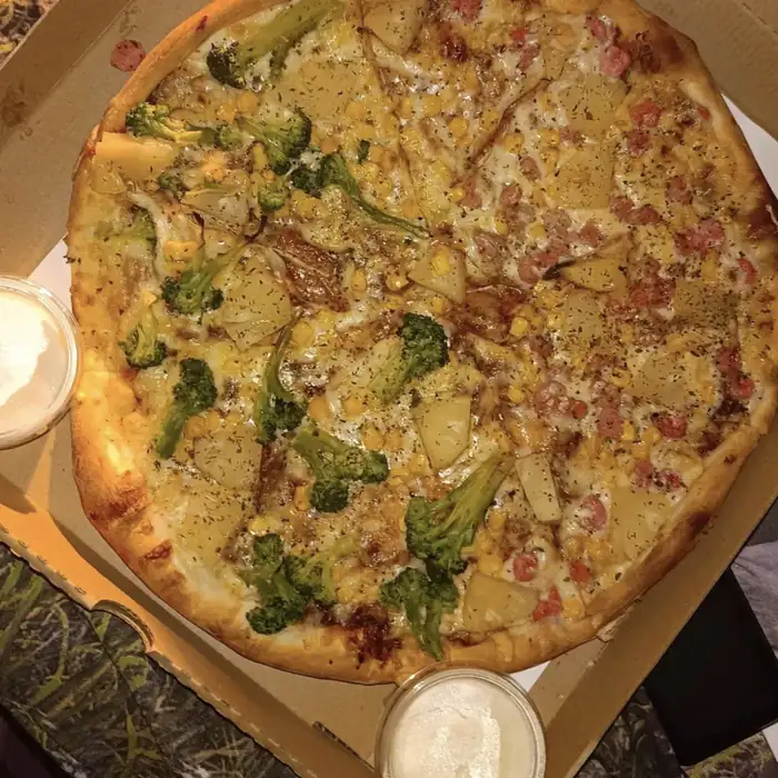Pizza z brokułami i boczkiem w kartonie z sosem czosnkowym