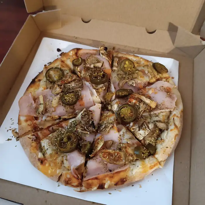 Pizza z jalapeño i szynką w otwartym pudełku