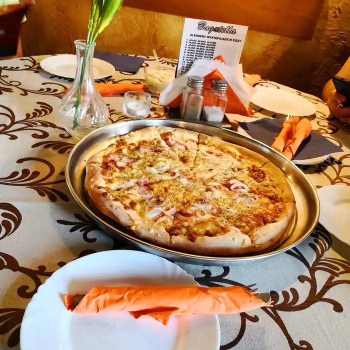 Pizza na metalowej tacy na stole z obrusem